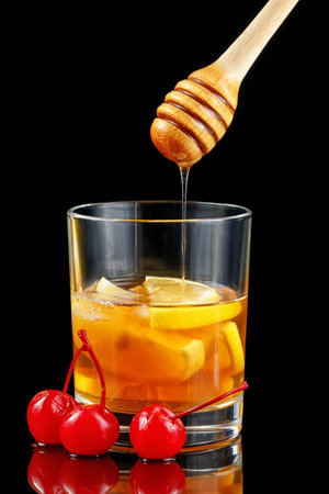 Lemon cocktail with cherry, honey and ice. Whiskey sour popular alcoholic cocktail with bourbonの写真素材