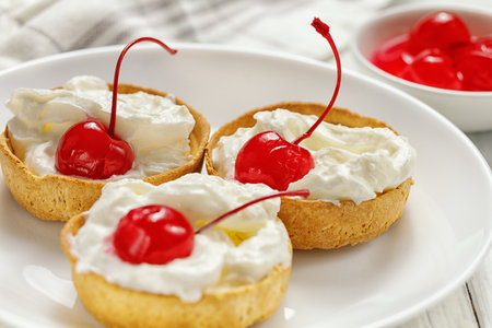 Baskets of pastries with cherry and cream. shortbread basket with cream and cherryの写真素材
