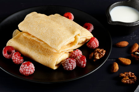 Pancakes with raspberries and nuts on a black plate. homemade pancakes with raspberriesの写真素材