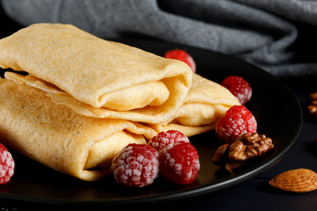Pancakes with raspberries and nuts on a black plate. homemade pancakes with raspberriesの写真素材