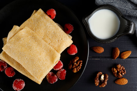 Pancakes with raspberries and nuts on a black plate. homemade pancakes with raspberriesの写真素材