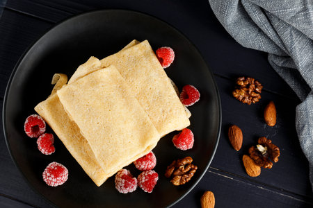 Pancakes with raspberries and nuts on a black plate. homemade pancakes with raspberriesの写真素材