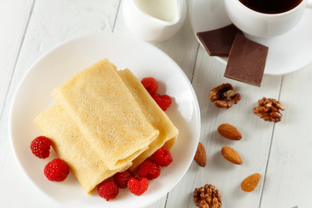 Pancakes with raspberries in coffee and milk. Sweet breakfast.の写真素材