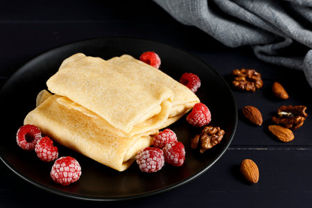 Pancakes with raspberries and nuts on a black plate. homemade pancakes with raspberriesの写真素材