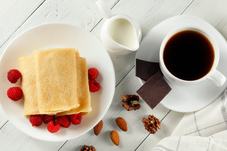 Pancakes with raspberries in coffee and milk. Sweet breakfast.の写真素材