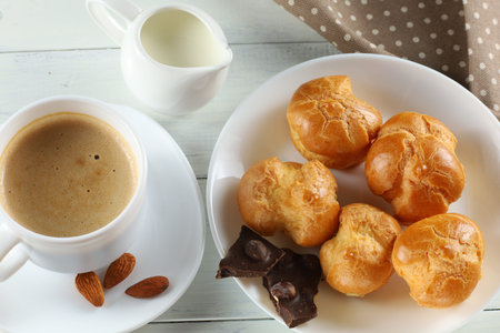 eclairs with chocolate, cappuccino and milk. Sweet breakfast. Vanilla eclair and a cup of coffeeの写真素材