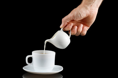 Coffee with milk. Milk is poured into a cup with coffee. Adding milk to a cup of coffeeの写真素材