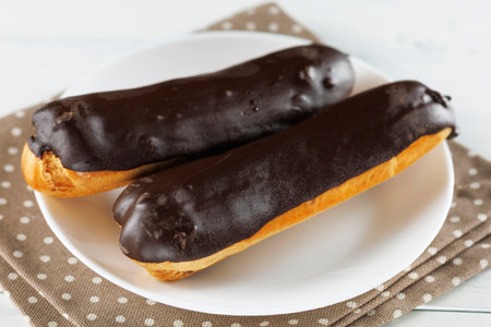 Chocolate eclairs in a white plate close-up.の写真素材