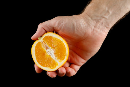 Cut orange in hand close-up isolateの写真素材