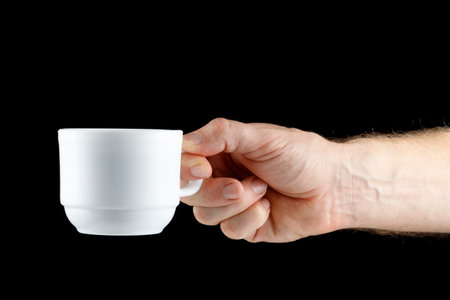 Hand holding white cup on black isolateの写真素材
