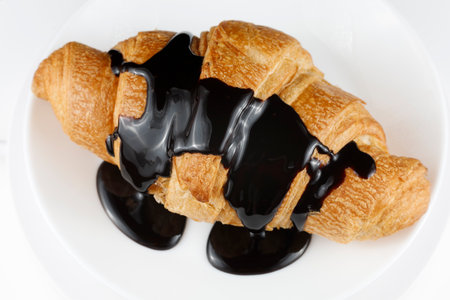 Chocolate poured on croissant close-up. Chocolate with a croissant on a plate.の写真素材