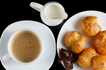 eclairs with chocolate, cappuccino and milk. Sweet breakfast. Vanilla eclair and a cup of coffeeの写真素材