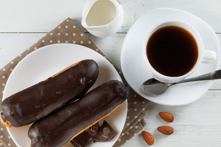 Chocolate eclairs with coffee and milk. Chocolate eclairs with coffee and milk. Chocolate eclairs on plate with coffeeの写真素材