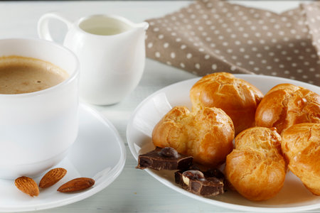 eclairs with chocolate, cappuccino and milk. Sweet breakfast. Profiteroles with creamの写真素材