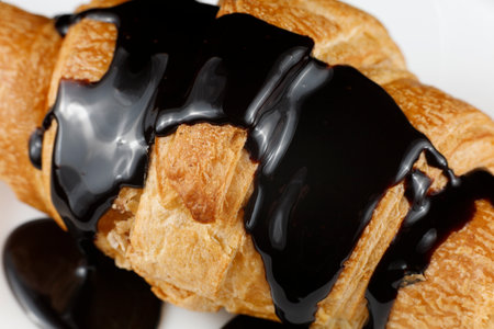 Chocolate poured on croissant close-up. Chocolate with a croissant on a plate.の写真素材