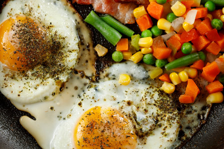 Fried eggs with vegetables in a pan.の写真素材