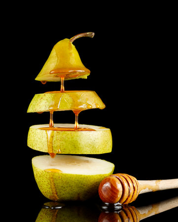 Pear with honey on black. Delicious fruit dessert. Honey flows down the pear.の写真素材