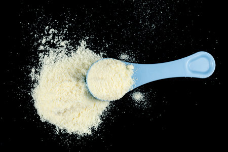 Baby food and a blue spoon. Yellow powder for baby food.の写真素材