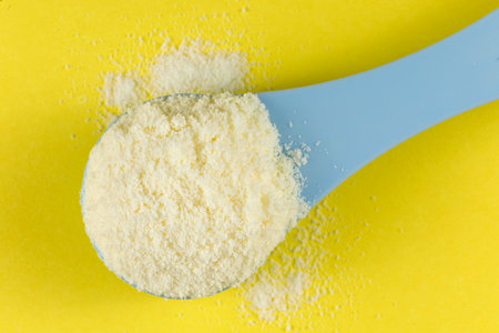 Baby food and a blue spoon. Yellow powder for baby food.の写真素材