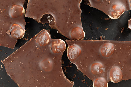 Pieces of chocolate with nuts on black close-upの写真素材