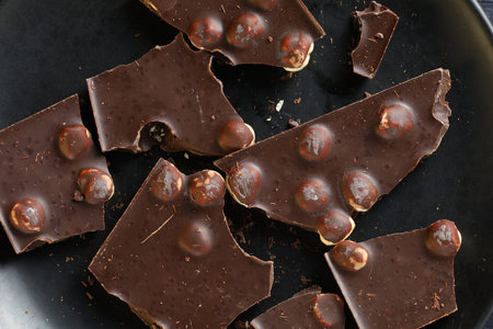 Chocolate with nuts on black. Dark chocolate pieces close-up.の写真素材