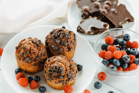 Chocolate muffins with berries. Appetizing cupcakes on a white background.の写真素材