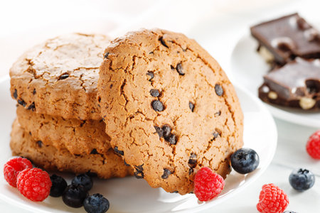 Oatmeal cookies with chocolate and berries on white. round cookies with dried fruitsの写真素材