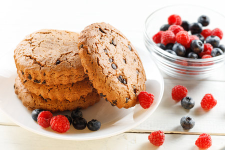 Oatmeal cookies with chocolate and berries on white.の写真素材