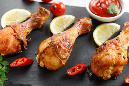 Fried chicken legs with tomatoes and lemon.の写真素材