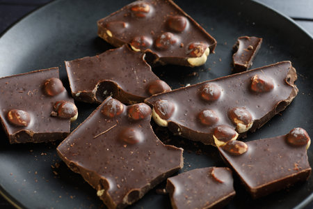 Chocolate with nuts on black. Dark chocolate pieces close-up.の写真素材