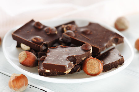 Broken chocolate with nuts in a white plate.の写真素材