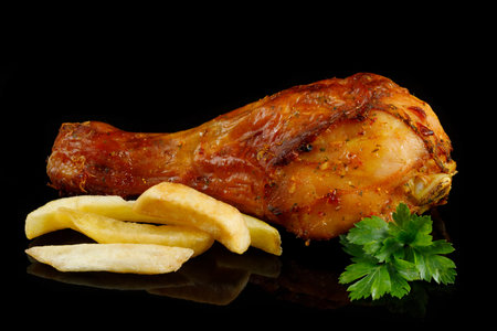 Fried chicken leg with greens on black.の写真素材