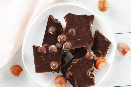 Broken chocolate with nuts in a white plate.の写真素材