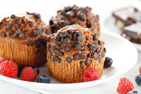 Chocolate muffins with berries. Appetizing cupcakes on a white background.の写真素材