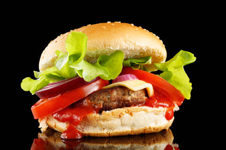 Burger with cutlet, tomato, cheese and greens. Fresh tasty burger isolated on black backgroundの写真素材