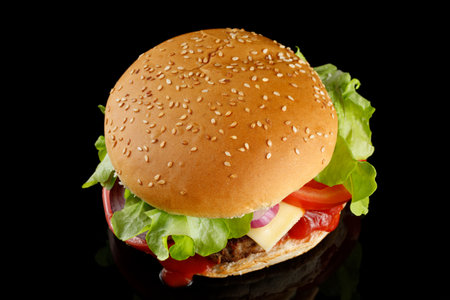 Burger appetizing top view on black. Fresh hamburger with lettuce, tomato and ketchup.の写真素材