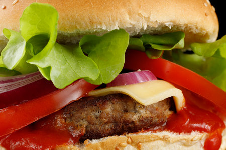 Burger with cutlet, tomato, cheese and greens. Fresh tasty burger isolated on black backgroundの写真素材