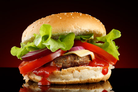 Burger with cutlet, tomato, cheese and greens. Fresh tasty burger isolated on black backgroundの写真素材