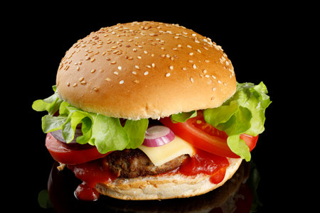 Burger with cutlet, tomato, cheese and greens. Fresh tasty burger isolated on black backgroundの写真素材