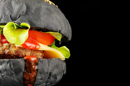 Black burger close-up. Burger with tomatoes, greens, onions and meat. place for text cope spaceの写真素材
