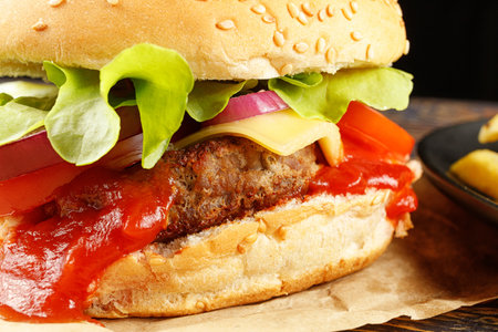 Tasty burger close-up. Burger with tomatoes, greens, onions and meat.の写真素材