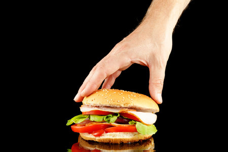 Burger in hand isolate on black.の写真素材