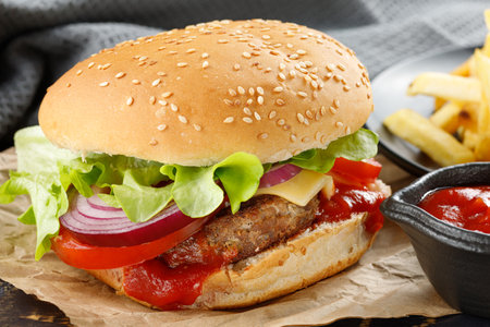 Burger with cutlet, tomato, cheese and greens. Fresh tasty burger isolated on black backgroundの写真素材
