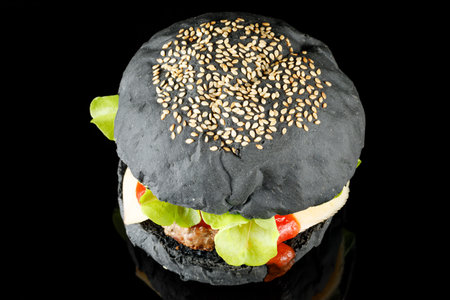 Black burger with lettuce, tomato, cheese and cutlet top view.の写真素材