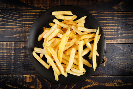French fries in a black plate on the table. Appetizing fried potatoes.の写真素材