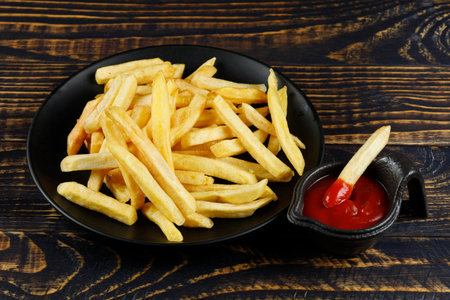 French fries in a black plate with sauce. Appetizing fried potatoes.の写真素材