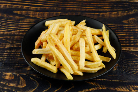 French fries in a black plate on the table. Appetizing fried potatoes.の写真素材