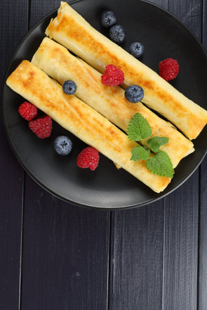 Pancakes rolls with raspberries and blueberries. Traditional breakfast and food.の写真素材