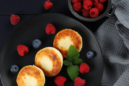 Cottage cheese fritters in a plate with berries.の写真素材