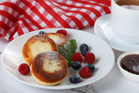 Cottage cheese fritters in a plate with berries. Healthy breakfast served with tea, cottage cheese fritters, pancakesの写真素材